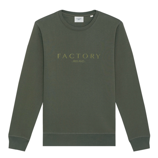 A green sweatshirt with 'Factory Ireland' embroidered on the front, set-in sleeves, and a flatlock topstitch on the seams.
