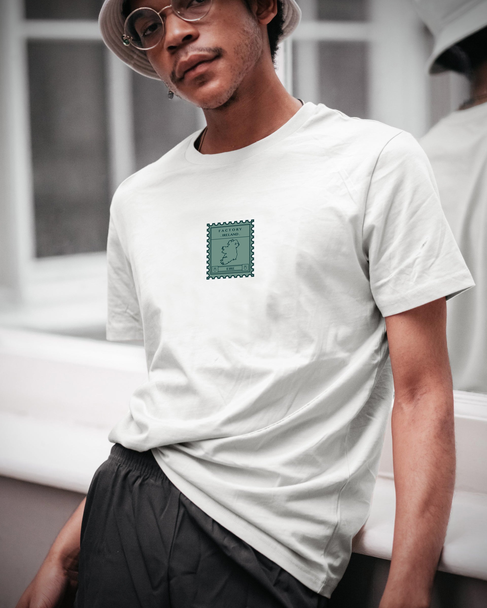 Person wearing a white t-shirt with a green logo in an indoor setting